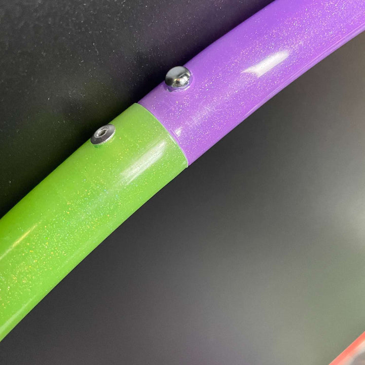 A UV green and purple glitter sectional hula hoop connection. l 2 piece hula hoop on a black background