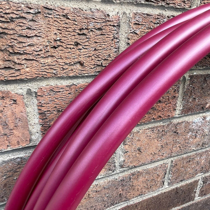 Black cherry deep red polypro hula hoops against a brick wall